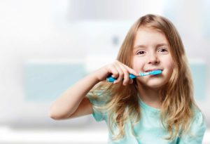 little girl in blue brushing teeth